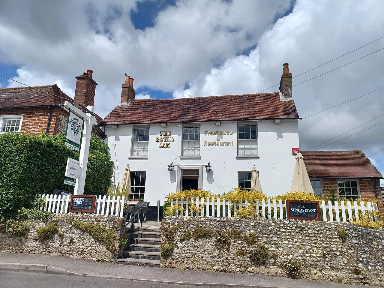 The Royal Oak on Pook Lane, East Lavant, behind its flint wall and white picket fence