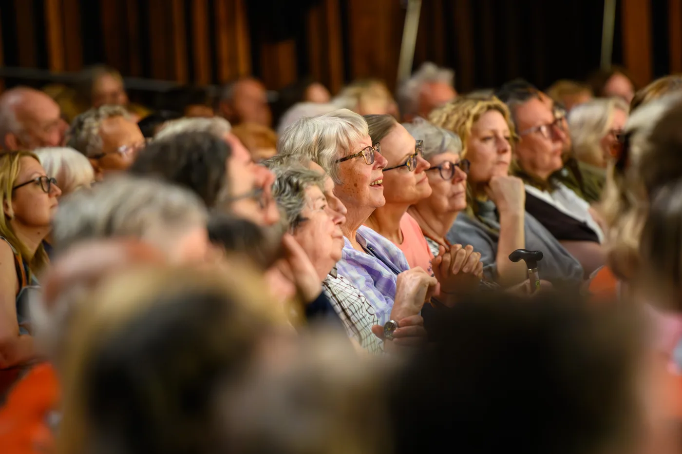 Rows of audience members laughing and applauding in a theatre